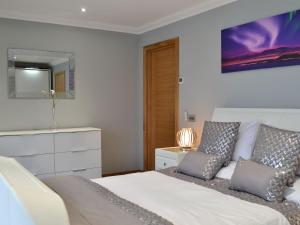 a bedroom with a bed and a tv on the wall at Skippers Retreat in Trumisgarry