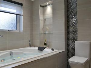 een badkamer met een bad, een toilet en een raam bij Skippers Retreat in Trumisgarry