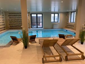 - une grande piscine avec des chaises et une table dans un bâtiment dans l'établissement LA TOUR AUX CRABES près de la plage, à Dieppe