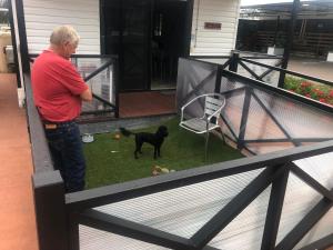 Kilcoy Motel في Kilcoy: رجل يقف على شرفة مع كلب أسود