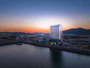 Gwangyang Lacky Hotel في Gwangyang: مبنى طويل بجوار نهر مع غروب الشمس