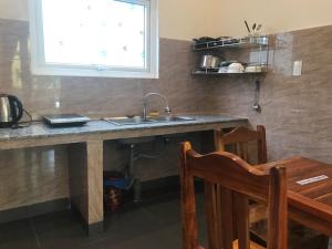 d'une cuisine avec un évier, une table et une fenêtre. dans l'établissement Sun & Wind Paradise Bungalow, à Duong Dong