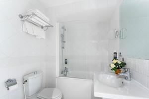 La salle de bains blanche est pourvue de toilettes et d'un lavabo. dans l'établissement Hotel Caumartin Opéra - Astotel, à Paris