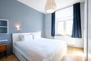 ein Schlafzimmer mit einem weißen Bett und einem Fenster in der Unterkunft Charmant Appartement 1 chambre avec balcon proximité Cinquantenaire in Brüssel