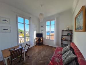 - un salon avec un canapé, une table et des fenêtres dans l'établissement Les Lauriers, à Villefranche-sur-Mer