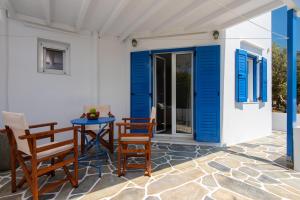 a patio with blue shutters and a table and chairs at KALYPSO ACCOMMODATION SIFNOS in Vathi