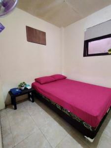 um quarto com uma cama rosa e uma mesa em Ijen Basecamp & Homestay em Ketapang