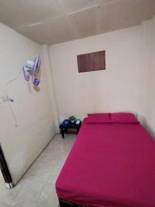 um quarto com uma cama rosa e um telefone em Ijen Basecamp & Homestay em Ketapang