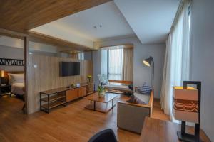 a living room with a couch and a tv at BATIQA Hotel Lampung in Bandar Lampung