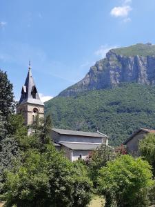 a church with a steeple in front of a mountain at Maison Milla in Saint-Égrève