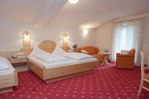 a bedroom with two beds and a living room at Hotel Garni Rifflsee in Sankt Leonhard im Pitztal