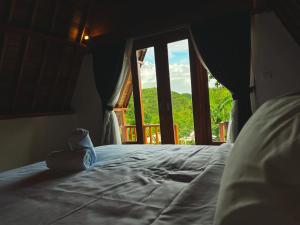 Bett in einem Zimmer mit einem großen Fenster in der Unterkunft dbelish village & resto in batumadeg