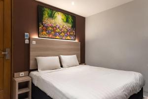 a bedroom with a white bed with a painting on the wall at TwoSpaces Living at Pakis Residence in Wonokitri 2