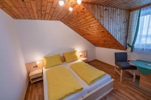 ein Schlafzimmer mit einem Bett mit gelben Kissen und einem Schreibtisch in der Unterkunft Bauernhof Oberlöffele in Jenig