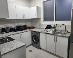 a kitchen with a sink and a washing machine at Fabulous 1BHK Jadaf Water Front Near Metro Station in Dubai