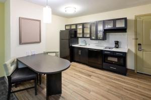 a kitchen with a table and a black refrigerator at Candlewood Suites - Rochester Mayo Clinic Area in Rochester