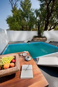 a table with a basket of fruit next to a swimming pool at Hotel Nefeli in Skiros