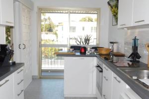 a kitchen with white cabinets and a large window at Spacious T2 "Jardin du Pont du Lys" with pool and parking in Antibes