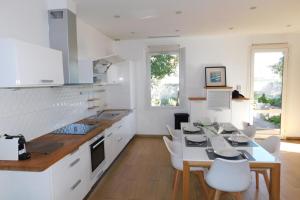 a kitchen with white cabinets and a table and chairs at "T3 ground floor of the villa "Les muguets" 3 minutes from the beach" in Vallauris