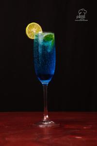 una bevanda blu in un bicchiere con una fetta di limone di Hotel Seasons Inn a Nellore