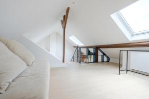 a living room with a couch and a skylight at Appartement tendance 1 chambre et mezzanine proximité Châtelain, Brugmann in Brussels