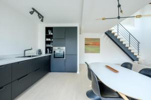 a kitchen with black cabinets and a table and a staircase at Appartement tendance 1 chambre et mezzanine proximité Châtelain, Brugmann in Brussels