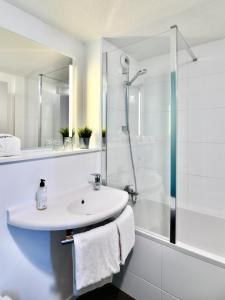 een witte badkamer met een wastafel en een douche bij ibis budget Vannes in Vannes