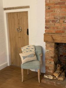 Pokój z krzesłem i ceglanym kominkiem w obiekcie Pinnacle Cottage grade II listed home at the coast w mieście Heacham