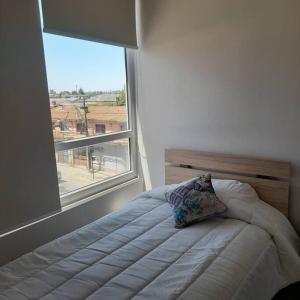 a bed with a pillow in a room with a window at Departamento central en Temuco in Temuco