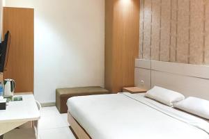 1 dormitorio con cama blanca y escritorio en TwoSpaces Living at KR Hotel, en Palembang