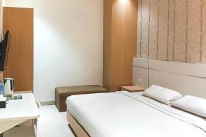 a bedroom with a white bed and a desk at TwoSpaces Living at KR Hotel in Palembang