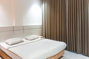 1 dormitorio con 1 cama grande y ventana en TwoSpaces Living at KR Hotel, en Palembang