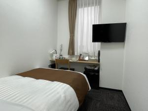 Habitación de hotel con cama, escritorio y TV. en Ueno Urban Hotel Annex, en Tokio