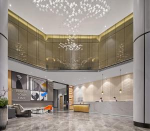 una hall con lampadario pendente in un edificio di Fengyue Light Shang Hotel Guangzhou Baiyun Airport Store a Canton