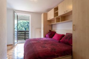 a bedroom with a bed with red sheets and a window at Iglica Apartments - First Floor in Bohinjska Bela