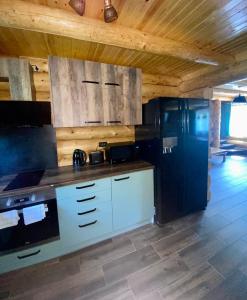 a kitchen with white cabinets and a black refrigerator at Bellevue Chalet in Râşnov