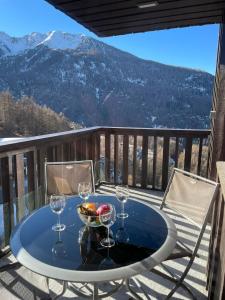 a table with wine glasses and a bowl of food on a balcony at Appartement Les Orres au pied des pistes ! in Les Orres