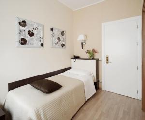 a white bedroom with a bed and a mirror at Hotel Aurora in Pavia