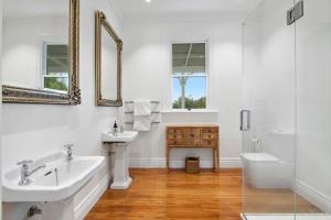 a white bathroom with two sinks and a toilet at Botham's Beauty - Blenheim Holiday Home in Blenheim +14 photos