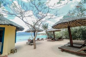 a beach with chairs and umbrellas and the ocean at Whale Island Resort in Dam Mon