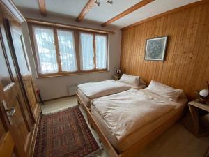 two beds in a room with wooden walls and windows at Jack in Schwarzsee