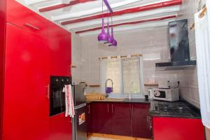 a kitchen with red cabinets and a red wall at MY SUN V.I.P COTTAGE @ KARIBU PALMS RESORT in Diani Beach