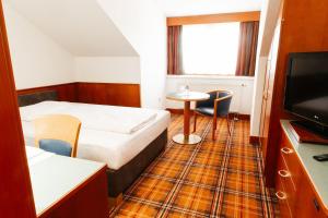 ein Hotelzimmer mit einem Bett, einem Tisch und einem TV in der Unterkunft Hotel Liebmann in Lassnitzhöhe