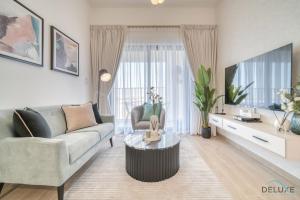 uma sala de estar com um sofá e uma televisão em Serene 2BR at The Nook Wasl Gate Jebel Ali by Deluxe Holiday Homes em Dubai