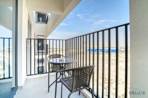 uma varanda com mesa e cadeiras e vista para a praia em Serene 2BR at The Nook Wasl Gate Jebel Ali by Deluxe Holiday Homes em Dubai