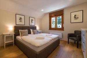 a bedroom with a large bed and a chair at Mostnica Cottage in Bohinj