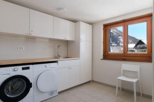 a kitchen with a washing machine and a window at Mostnica Cottage in Bohinj