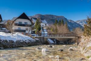 a bridge over a river in a town with snow at Mostnica Cottage in Bohinj