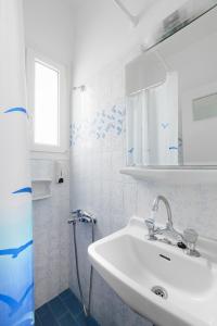 een witte badkamer met een wastafel en een spiegel bij Villa George in Batsi