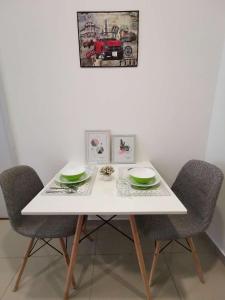 un tavolo bianco con due sedie, un piatto e ciotole di LAVENDER Suite @ I-City a Shah Alam